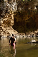 Sportive shirtless guy with a pink short swimming in xien lap cave, Thakhek loop, Laos