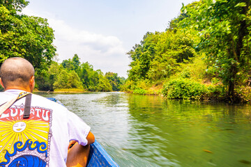 Short hair guy from behing in a canoe kayak on the lake of Kong lor cave, with green mountains in the background, Thakhek loop, Laos