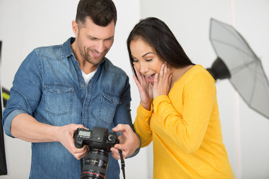 professional photographer showing pictures to model in studio