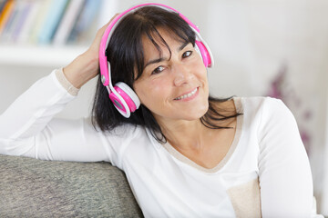 happy mature woman listening to music at home light effect