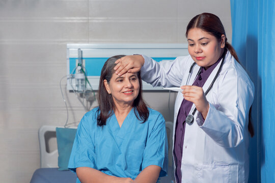 Indian female doctor using thermometer while check up to senior patient at hospital. - Powered by Adobe