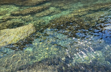 Fototapeta na wymiar Sea water underwater stones pebbles in clear shiny waters.