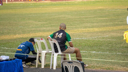 Substitute rugby player waiting on a chair in Vientiane, Laos