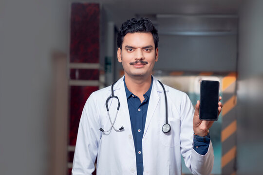 Indian doctor showing smartphone screen at hospital. - Powered by Adobe