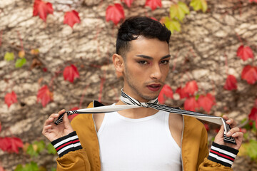 Portrait of biracial transgender man looking at camera, with rocks and leaves in background