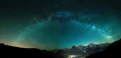 Milky Way arc and stars in night sky over the Swiss Alps with the famous alpen peaks Eiger, Monch and Jungfrau down right in the background