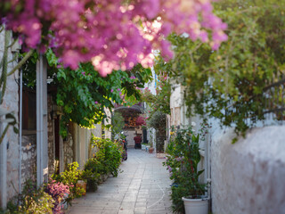 Fototapeta na wymiar Blooming bougainvillea, streets of the old town of Bodrum, Turkey. Happy traveler woman in white elegant outfit walking by romantic streets . Summer travelling