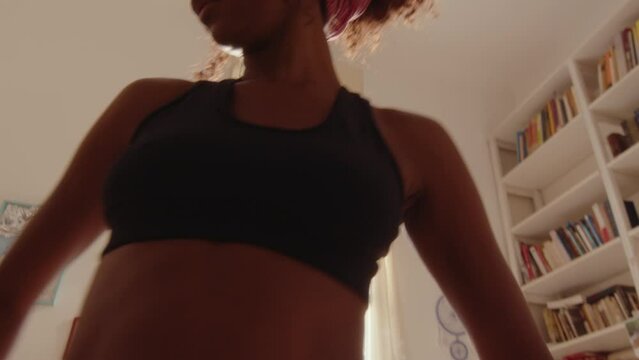 Young beautiful barefoot black girl dancing gracefully in the living room on a sunny day, making choreo and feeling inspired. Tilt-up, low angle shot