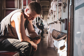 a man using a phone in the aisle of a second-class carriage of a high-speed train waiting for his stop, the background is blurred