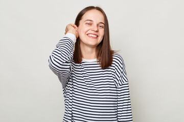 Happy face. Positive emotions. Smiling attractive cheerful brown haired woman wearing striped shirt posing isolated over gray background
