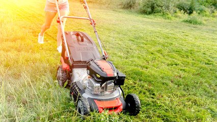 a girl with a lawn mower mows a beautiful lawn