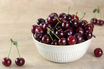 A bowl of fresh red cherries on a beige background. copy space.
