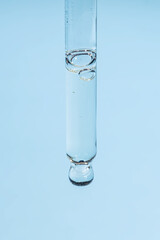 Cosmetic pipette with aloe or hyaluron serum or essential oil on light blue background. Skin care anti-aging treatment.