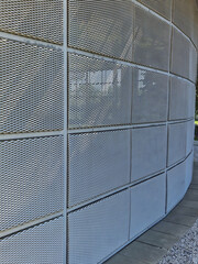 steel cladding of a building with a expanded metal lattice structure. galvanized gray nets protect the industrial building. Blue sky in contrast to a silver background, round, wall