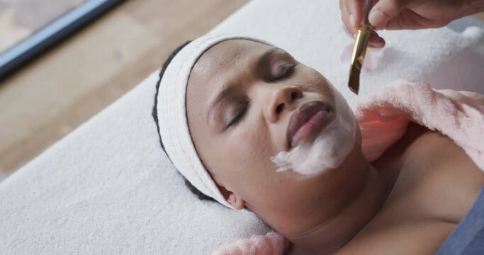 Beautician applying beauty mask on face of african american plus size woman, unaltered, slow motion