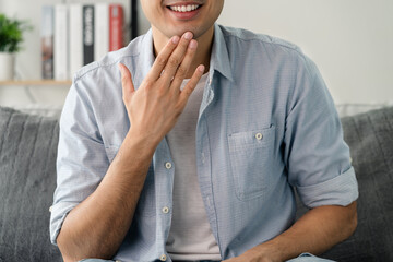 Happy young deaf man using sign Language to communicate with other people..
