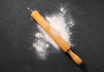 Scattered organic  flour with rolling pin on dark gray background. Homemade healthy food .concept.