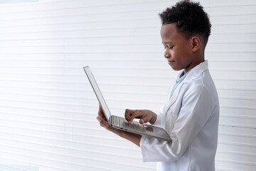 Side view of African boy using laptop, holding laptop computer in arm on white background