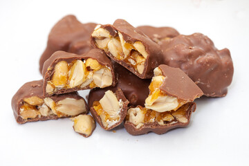 Chocolate covered peanut brittle pieces on white