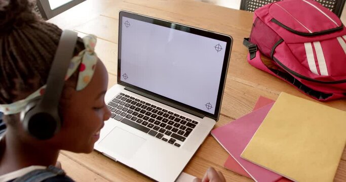 Happy african american girl in online class using headphones and laptop with copy space, slow motion