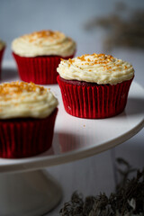 red velvet cupcake with icing and gold sprinkles on a cake stand