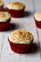 close up of red velvet cupcake with icing and gold sprinkles