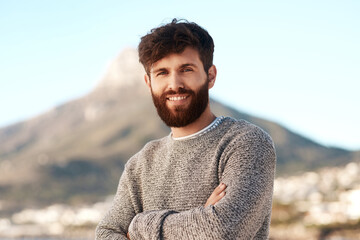 Nature portrait, arms crossed and happy man relax with outdoor wellness, vacation freedom and smile for peace. Summer sunshine, mountain and male person on travel holiday in Cape Town, South Africa