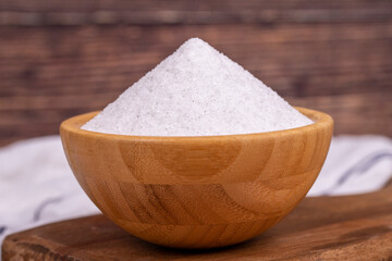 Natural minaret crystal non-iodized grinding salt on wooden background. Ground rock salt in wooden bowl. Close up