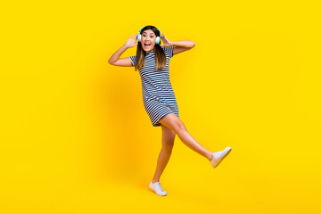 Fototapeta na wymiar Full length body photo of japanese girl listen her wireless earphones dance crazy overjoyed meloman isolated on yellow color background