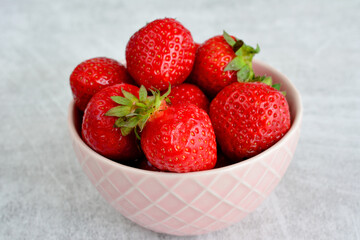 bowl with garden strawberries isolated on gray background, close up  