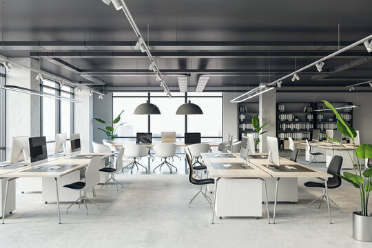 Front view of an open office interior with desks, computers, a concrete floor, and black ceiling. A window lets in natural light. Modern workspace design and business background. 3D Rendering