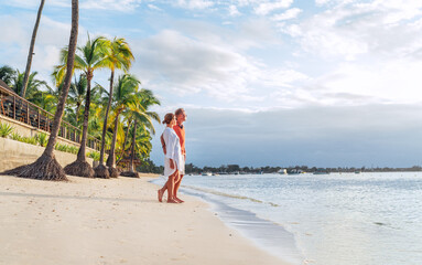 Couple in love hugging on sandy exotic beach while having evening walk by Trou-aux-Biches seashore on Mauritius island enjoying sunset. People relationship and tropic honeymoon vacations concept image © Soloviova Liudmyla