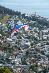 paraglider flying over suburban neighborhood with houses and trees in the background. sea point...
