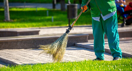 The janitor cleans the city street with a broom in the city. Street cleaning service. A worker...