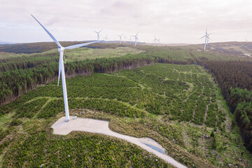 Aerial view on a wind farm turbine build in a rural country area with green forest. Making power...