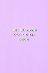 Top view of "it is okay not to be okay" quotes made out of beads on pastel background. motivation and success concept