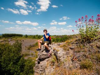 Obraz premium Slim athletic man on edge of a cliff, beautiful nature scene on a warm sunny day. Outdoor activity. Get out of town and adventure concept. Blue cloudy sky. Be active theme