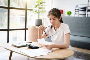 Stressed young woman holding papers in her hands calculating monthly house expenses, taxes,not enough income for expenses.