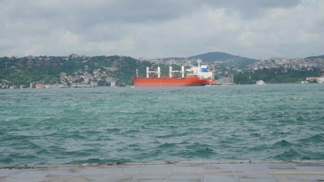 A cargo ship sails through the Bosphorus Strait on a summer day.