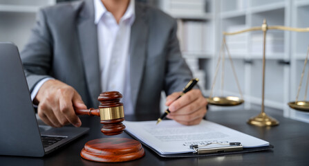 Justice and law concept.Male judge in a courtroom the gavel, working with digital tablet computer.