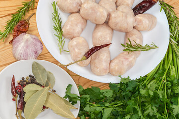Raw thick short sausages among spices and greens, close-up