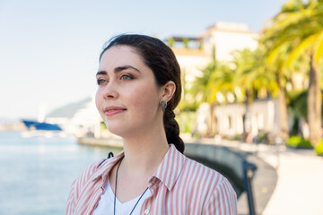 Portrait of young smiling Caucasian woman on background of sunny beach and sea. Summer and vacation. Concept of psychology and relax