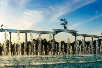 Memorial and rows of fountains illuminated by sunlight at sunset or sunrise in the Independence Square at summertime, Tashkent.