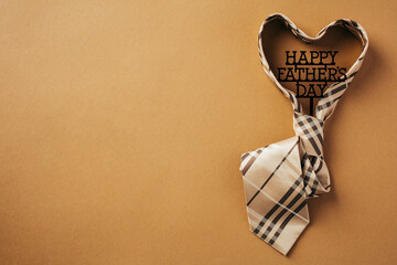 Happy Father's Day concept. Heart shaped necktie with sign Happy Fathers Day over brown background.