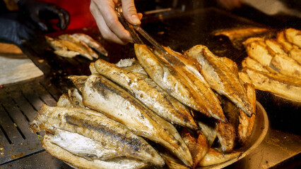 Closeup of dish full of roasted grilled fish. Cooking famous Turkish dish Balik Ekmek on street.