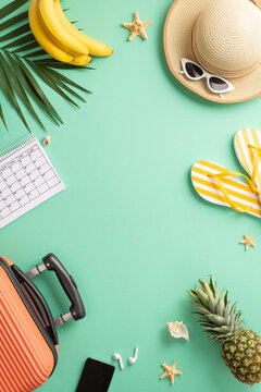 Tropical vacation concept. Top vertical view photo of a suitcase and straw hat with sunglasses, palm leaves and exotic fruit, calendar and flip-flops on isolated turquoise background with copyspace