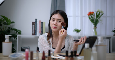 Beautiful young Asian woman blogger shows how to make up and use cosmetics