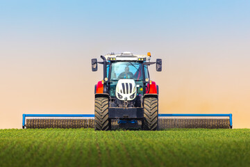 Fototapeta na wymiar Tractor with a roller tillage on spring field. Soil rolling supports germination and is the basis for good harvesting, organic farming and agronomy