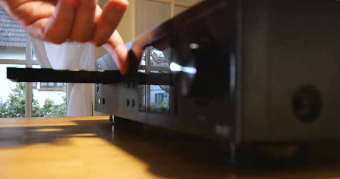 Man inserting CD to play - Experience rich, high-quality sound with this vintage hifi system. Enjoy your music with one touch, whether streaming wirelessly or playing your favorite CD.