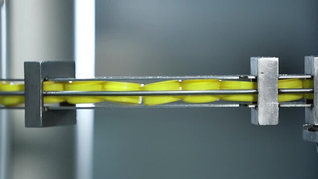 Close up of plastic bottle caps production in automated machine, yellow caps in a queue preparing for next step of manufacturing.